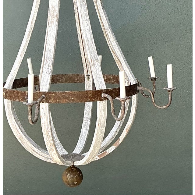 This vintage rustic chandelier embodies the character of timeworn craftsmanship, pairing weathered wood with hand-forged...