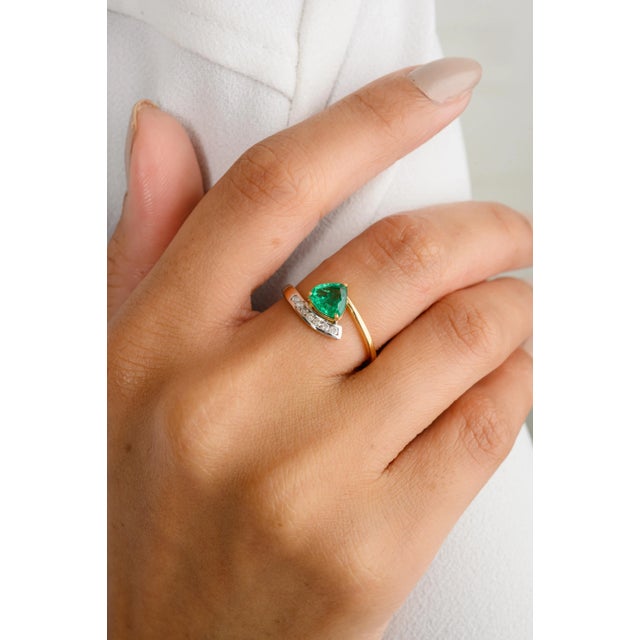 This exquisite wedding ring features a stunning 0.08 carat pear-cut green emerald, complemented by shimmering diamonds...