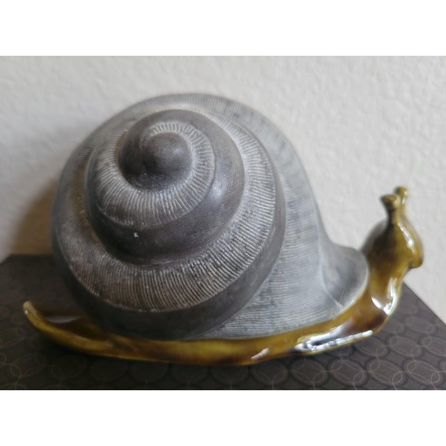 Vintage, charming decorative snail sculpture featuring a textured, stone‑like spiral shell paired with a smooth, glossy...