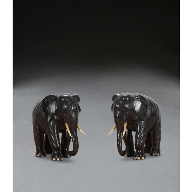 A charming pair of ebony elephants sculpted out of solid ebony, modelled in a striding stance, also more unusual having...