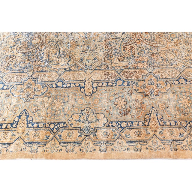 A Persian Kirman rug, the field in beige and blue with an unusual design of graceful elongated cusped cartouches formed by...