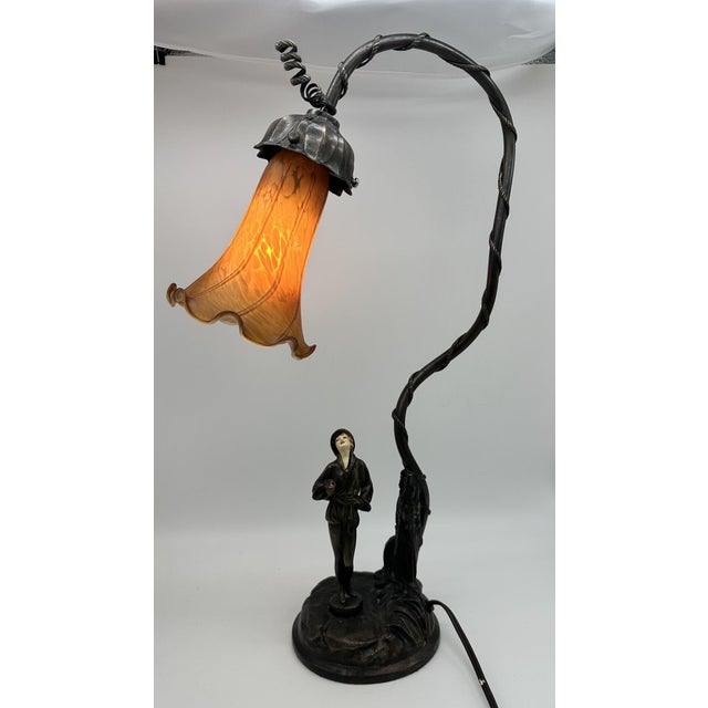 Desk or table lamp. Art Deco. Bronze-colored metal with figural of woman with celluloid face. Art glass shade. Circa 1920....