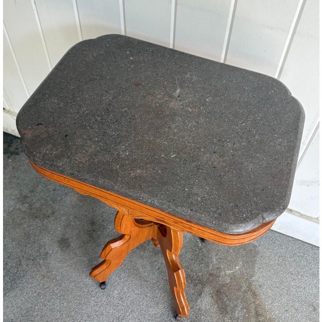 Eastlake style carved wood side table w/ grey marble top and original caster feet. Excellent condition.
