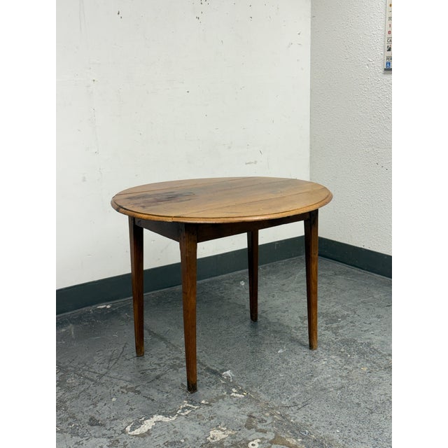 Design Plus Gallery presents an Antique French Drop Side Round Farm Table. The table features a round top with hinged drop...