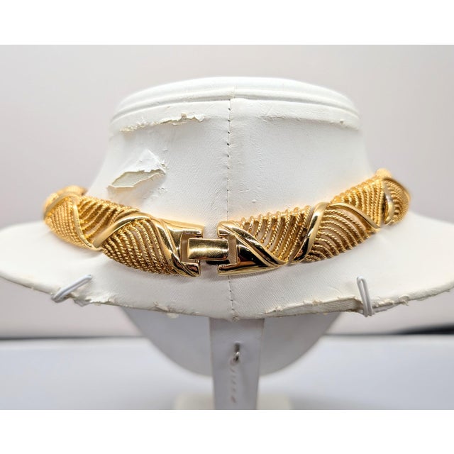 Circa 1990 Goldtone textured openwork wavy "ribbon" articulated collar necklace with fold over clasp. Marked "Napier" in...