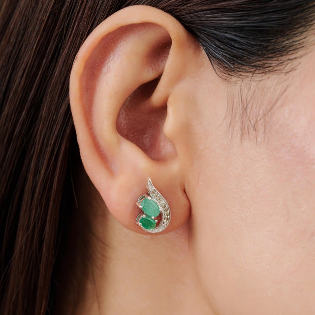Art Nouveau-inspired emerald and diamond stud earrings featuring 1.85 carats of oval-cut emeralds in an elegant, organic...