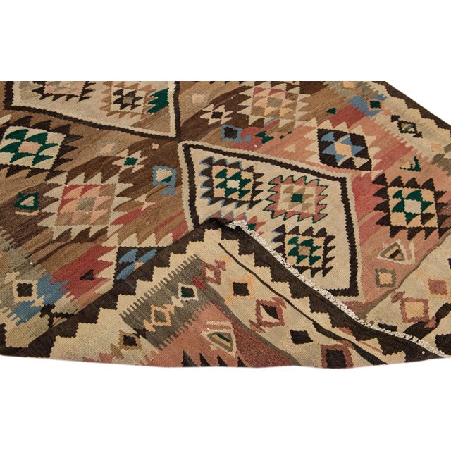 Beautiful vintage Turkish Kilim hand-knotted wool rug with a beige field. This piece has a brown frame with peach and...
