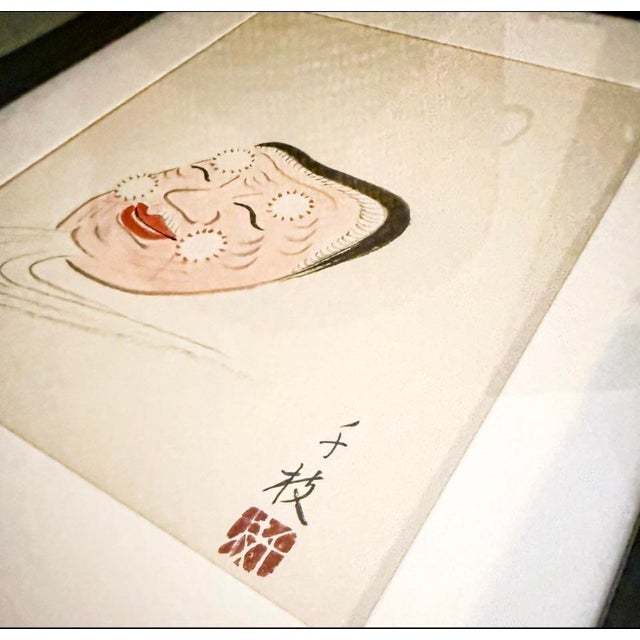 Vintage Framed Japanese Noh mask painting, which depicts a Noh mask, likely of the Okina or Hakushikijo type, typically...