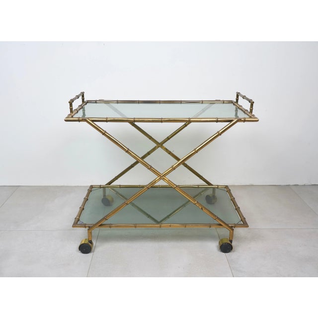 Elegant French bar trolley with solid faux bamboo brass frame and two smoked glass shelves. Marked "Rue Royal ". Its style...