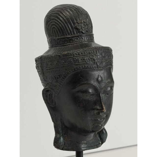 This mid-19th-century bronze Buddha head is a finely cast Southeast Asian sculpture, probably Thai, distinguished by its...