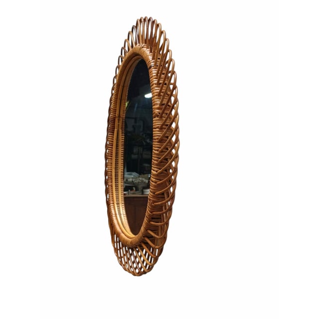 Italian rattan wall mirror (circa 1960s) by Franco Albini. The mirror has a complex weave of rattan in a series of...