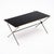 A sleek French mid-century coffee table combining a black glass top with a slender black metal frame and refined brass...