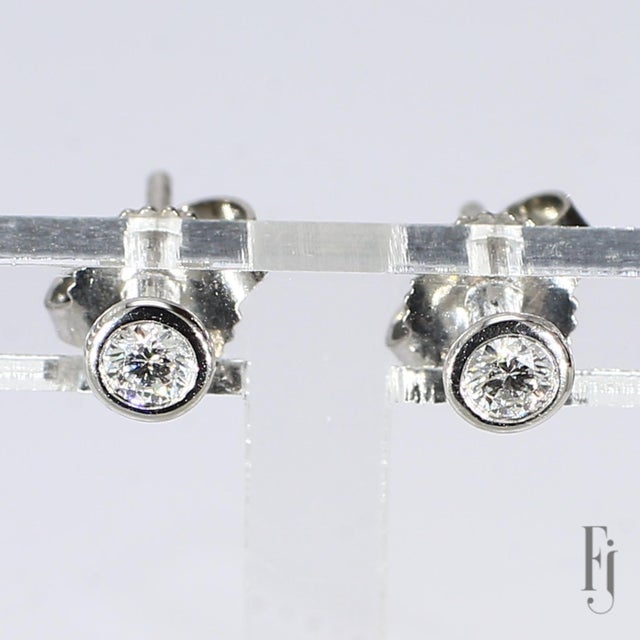 Here is a Pair of Platinum Stud Earrings by Tiffany & Co. featuring Two ~0.1ct. E/VS2 Round White Diamonds. Original...