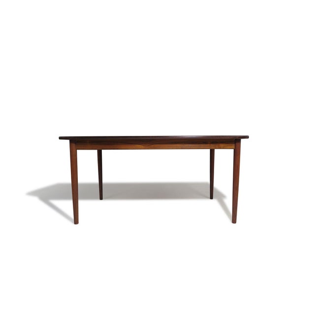 Danish Rectangular dining table handcrafted from Brazilian rosewood, featuring a top surface with wide book-matched grain...