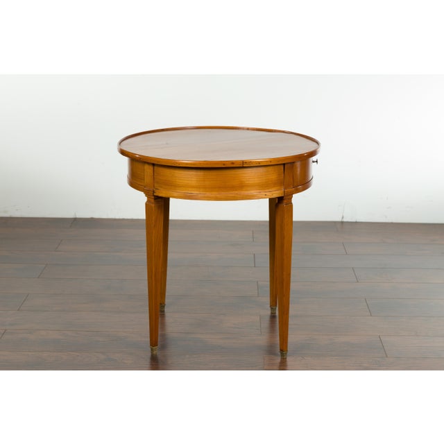A French Napoléon III period walnut side table from the mid-19th century, with single drawer, tapered legs and brass feet....