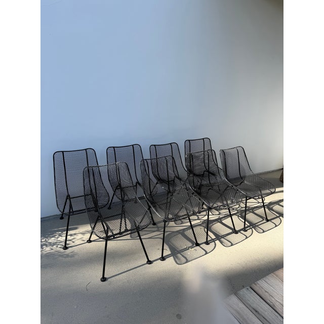 Set of eight (8) unmarked, classic MCM wrought iron outdoor dining chairs that have been painted black from white.