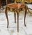 Elegant French-style side table featuring a sophisticated glass top that beautifully showcases the decorative artwork...