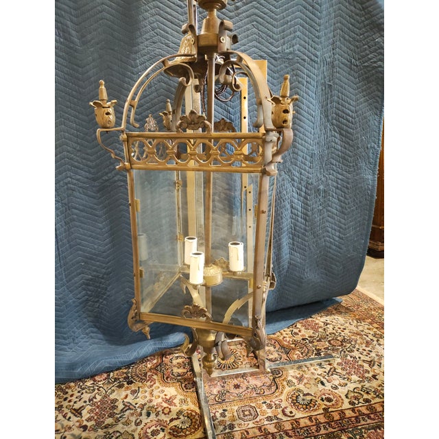 A striking French Louis XV–style brass hall lantern featuring a rectangular glass-paneled body framed by ornate Rococo...