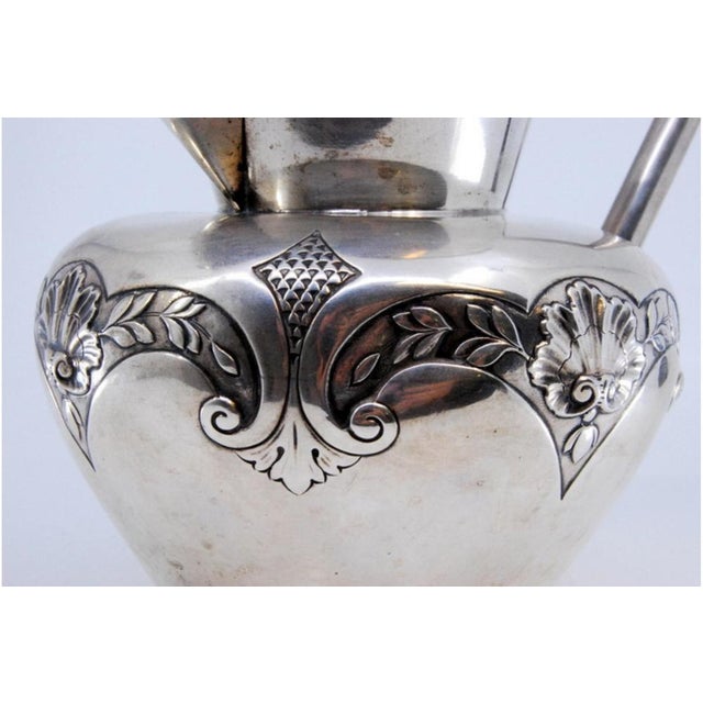 Silver Wine Jug with Raised Plant Motifs and Angular Handle, in Very Good conditions. Designed 1890 to 1919 This piece has...
