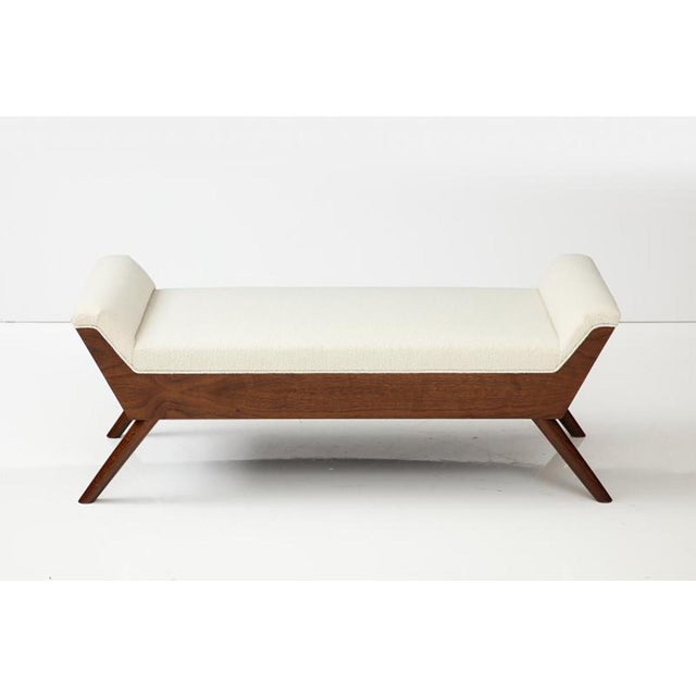 A contemporary Scandinavian inspired Modernist bench crafted in walnut with splayed legs and upholstered in an ivory...