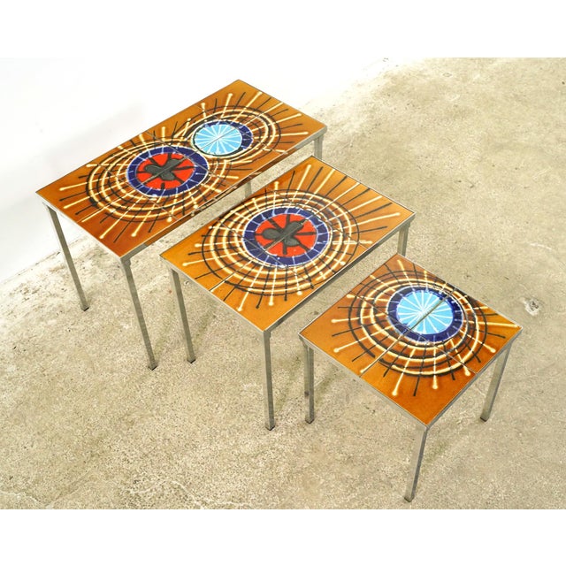 Mid Century style nesting tables with starburst design ceramic tops, paired with chrome steel frames. Attributed to a...