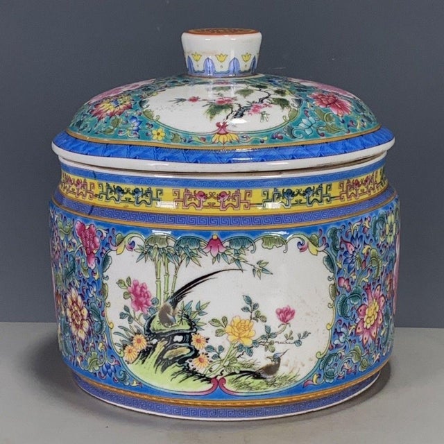 A vibrant Chinese porcelain covered jar featuring a bright blue ground. The jar is elaborately decorated with colorful...