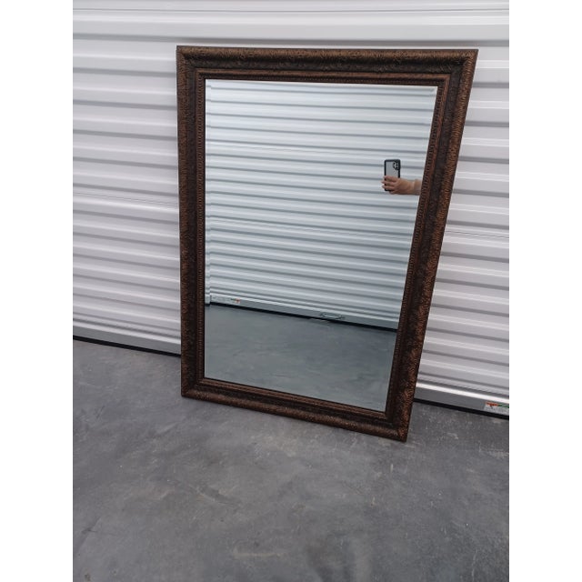 Vintage rectangular beveled mirror in a bronze tone elegant ornate embossed pattern and delicate texture inner edge. The...