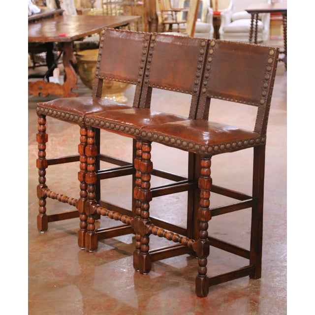 This striking set of three antique French bar stools was crafted in solid oak circa 1890 and reflects the bold...