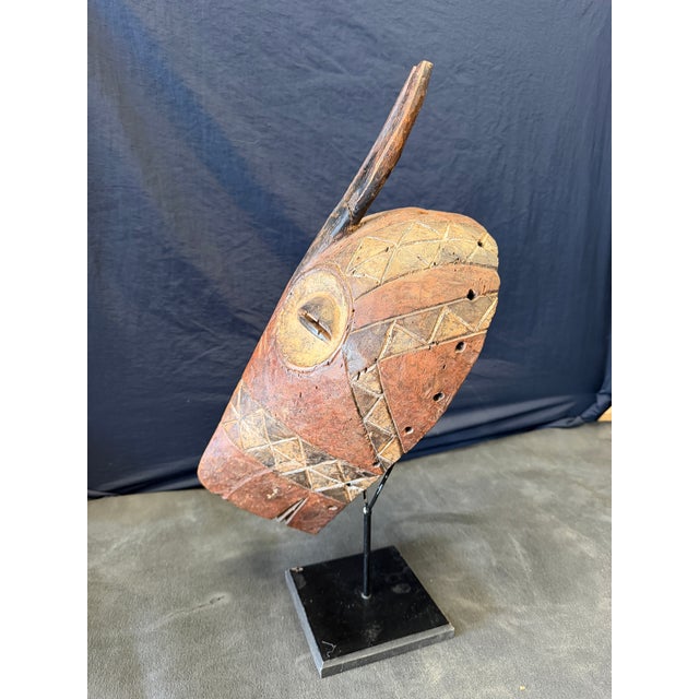 Striking vintage African hand-carved wood mask featuring an elongated face, tall antelope-form horns, slit eyes and deeply...
