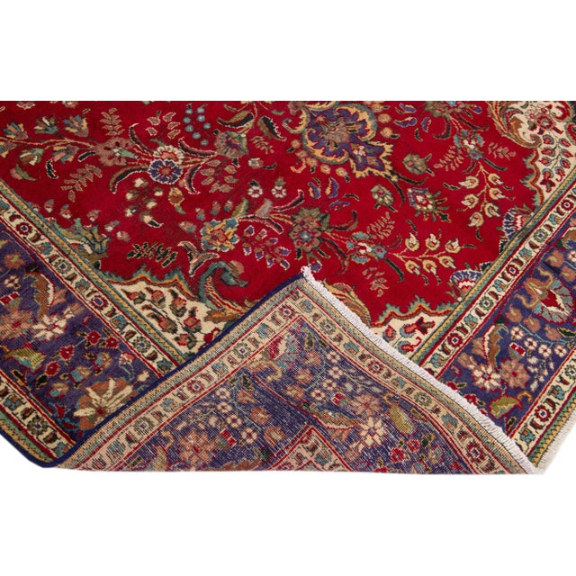 Beautiful vintage Persian Tabriz hand-knotted wool rug with a red color field. This piece has a navy blue frame and...