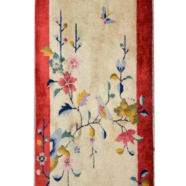 An early 20th century Chinese Art Deco rug with a champagne colored field surrounded by a wide cranberry border, and...