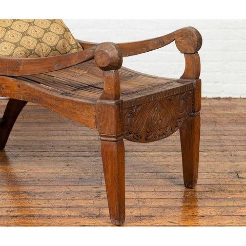 An antique Indonesian reclining plantation lounge chair with bamboo slats and carved motifs. Designed to provide a...
