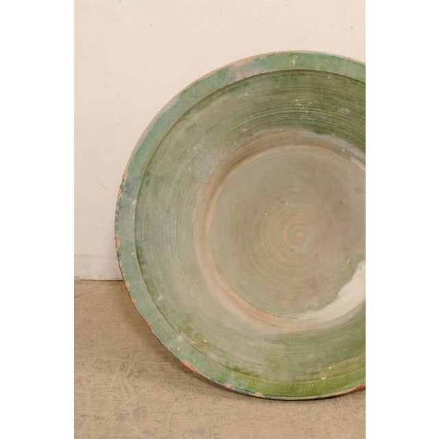 A Spanish glazed terracotta bowl from the early 20th century. This antique bowl from Spain is round in shape, with widest...