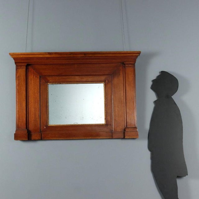 Empire walnut mantelpiece. Central mercury mirror and gilded frame with successive leaf carvings, column uprights. Italy,...