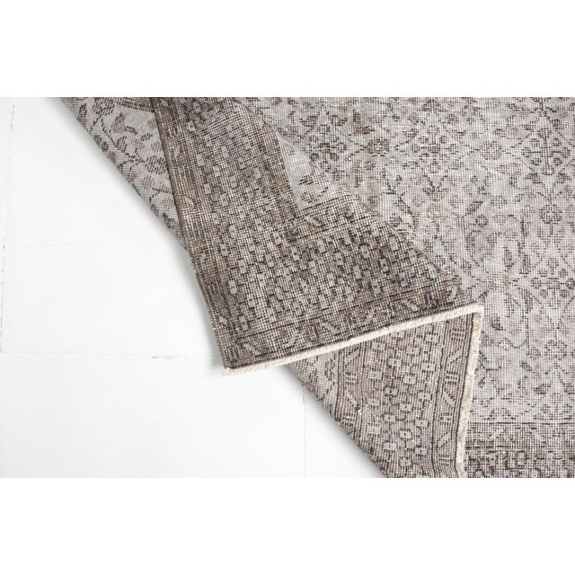 This is a vintage Turkish Oushak rug from the Mid 20th Century. The piece was hand-knotted.