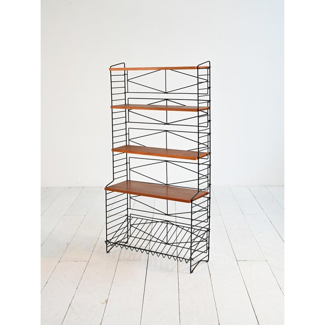 Iron frame with adjustable teak shelves and a lower magazine rack. 1960s freestanding bookcase. This 1960s freestanding...