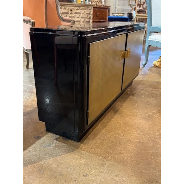 This Period Black Lacquered Art Deco Style Cabinet with Gold Leaf Doors is a stunning piece of furniture that exudes...