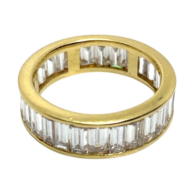 18K yellow gold eternity band featuring a continuous row of baguette-cut white diamonds. The diamonds are set in a channel...