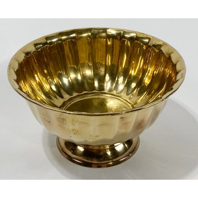 Vintage fluted brass bowl on pedestal base. Features scalloped rim and polished interior. Patina to brass.