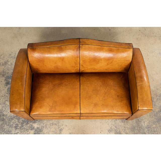 French Art Deco leather club sofa sourced in Paris, dating to the late 1920s–1930s. The sofa features a compact, squared...