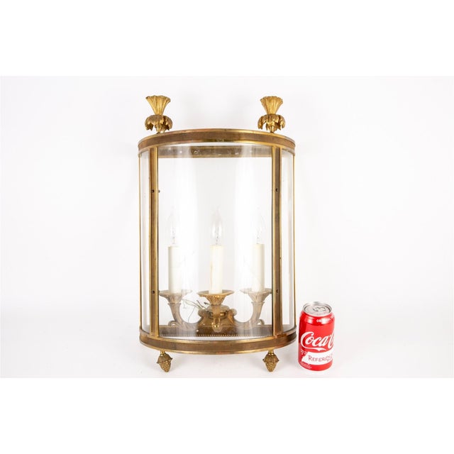 A vintage gilt brass demi-lune shaped wall lantern topped with two shell-and-foliate finials and matching acanthus...