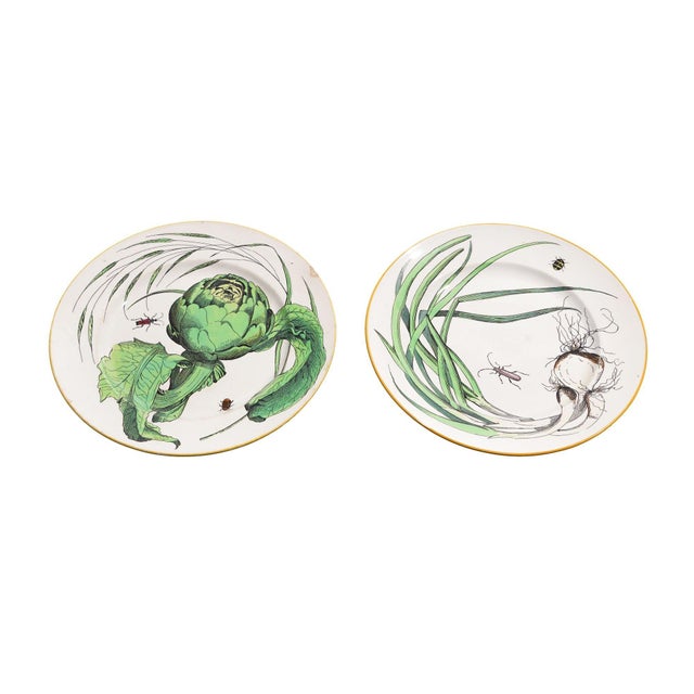 Pair of French glazed faience plates decorated with a hand painted vegetable transfer of scallions, artichokes, and...