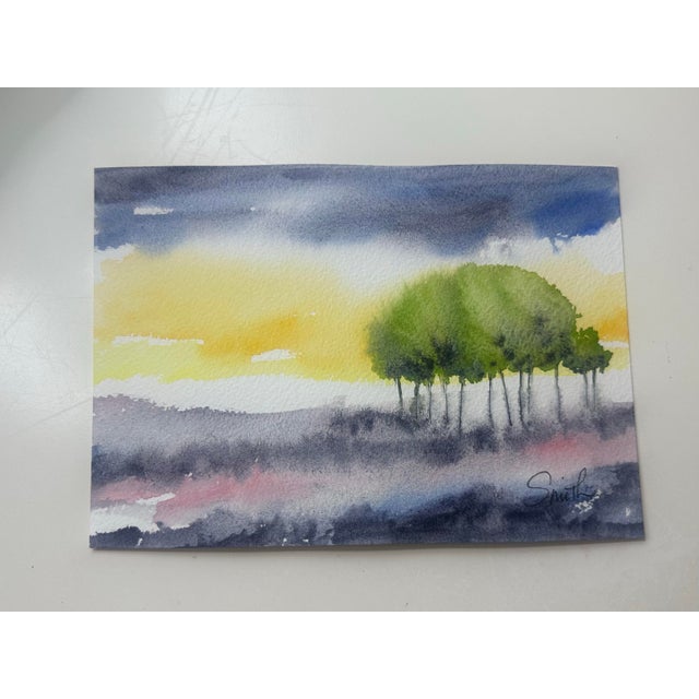 A striking watercolor landscape featuring a cluster of vibrant green trees set against a glowing yellow horizon and...