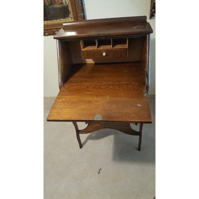 An elegant Turn-of-the-Century drop-front secretary desk crafted in tiger oak. This compact piece features slender...