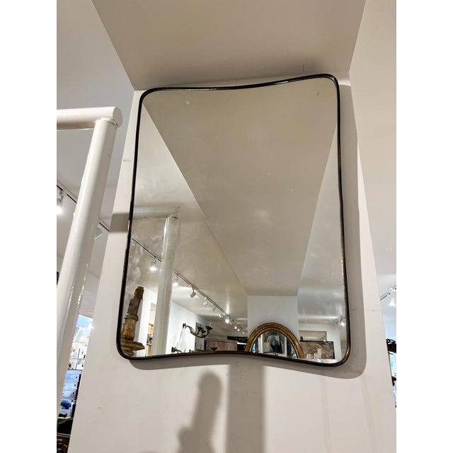Elegant Mid-century mirror with thin brass frame. Shield shaped and the perfect size for a powder room.