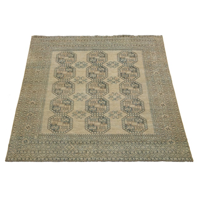 Antique Turkmen hand-knotted wool rug featuring a timeless beige color field. This Persian masterpiece showcases a...
