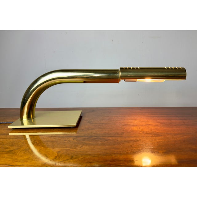 A circa 1970’s desk lamp features a sleek, minimalist tubular brass arm and a flat base by Rainbow Lamp Company,...