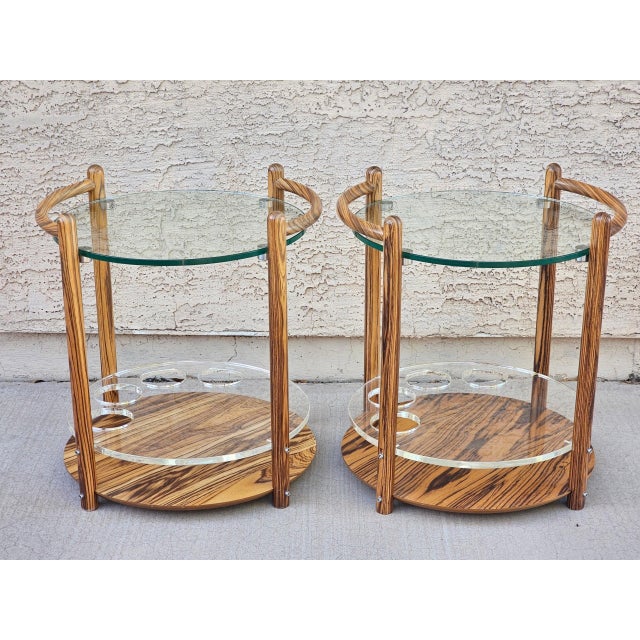 Stunning pair of 1980s zebrawood two-tier side tables with dramatic striped grain. Each features a round beveled glass...