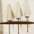 A wonderful large pair of French wall lamps composed of teak, polished brass, and gun metal enamel bodies with white glass...