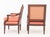 An elegant matched pair of Louis XVI-style stained mahogany armchairs, or fauteuils, combining restrained Neoclassical...